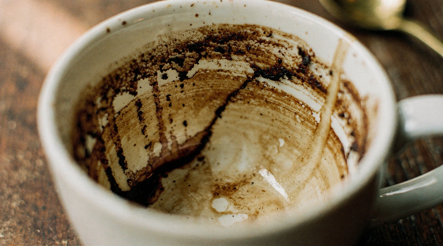 The dried inside of an upturned coffee cup showing dark patterns running from the rim toward the base